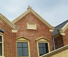Building showing decorative stone gable, copings, namestone and window surrounds.